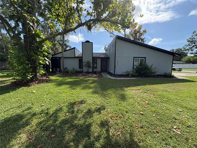 a view of a house with a yard garage and a large tree