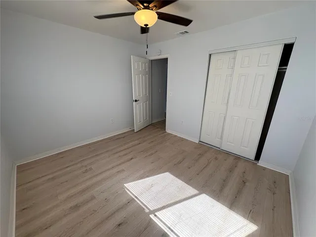 an empty room with wooden floor fan and windows