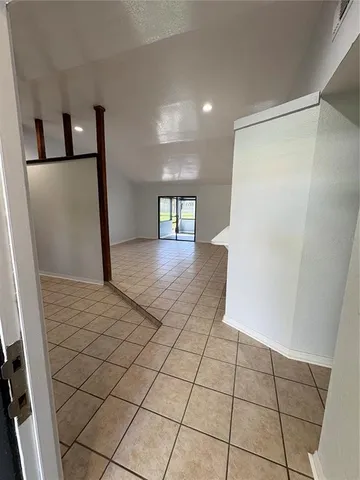 a view of a refrigerator in kitchen and an empty room in wooden floor