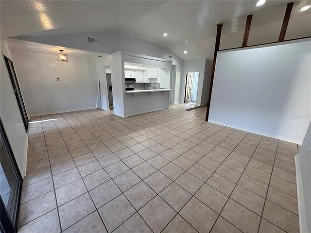 a view of an empty room and kitchen