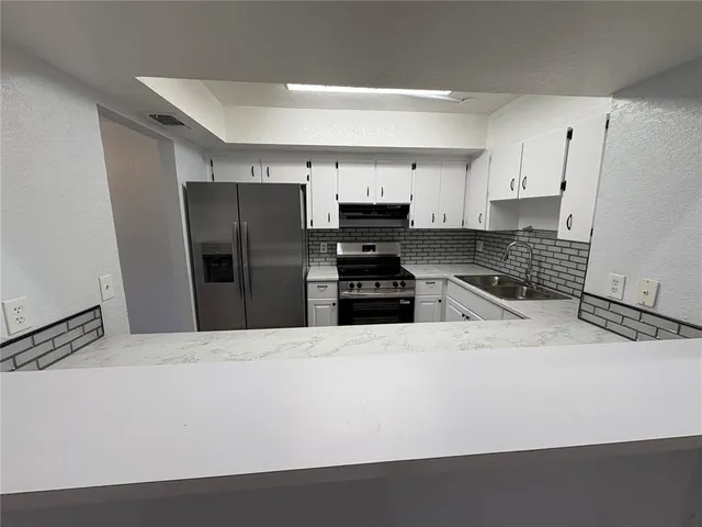 a kitchen with granite countertop a refrigerator and a stove top oven