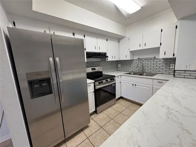 a kitchen with stainless steel appliances a refrigerator sink and cabinets