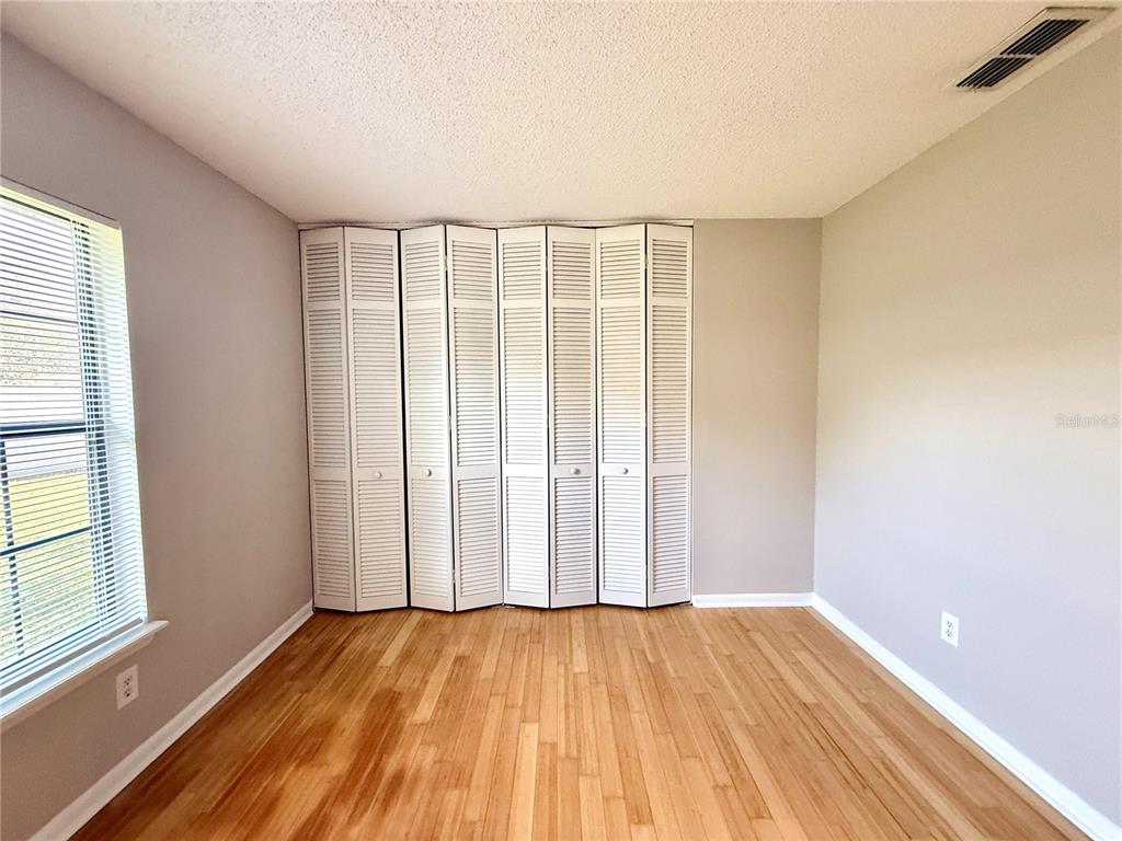 758 Warrenton Road Winter Park, FL 32792 - Photo 19 of 52 an empty room with wooden floor and windows with curtains