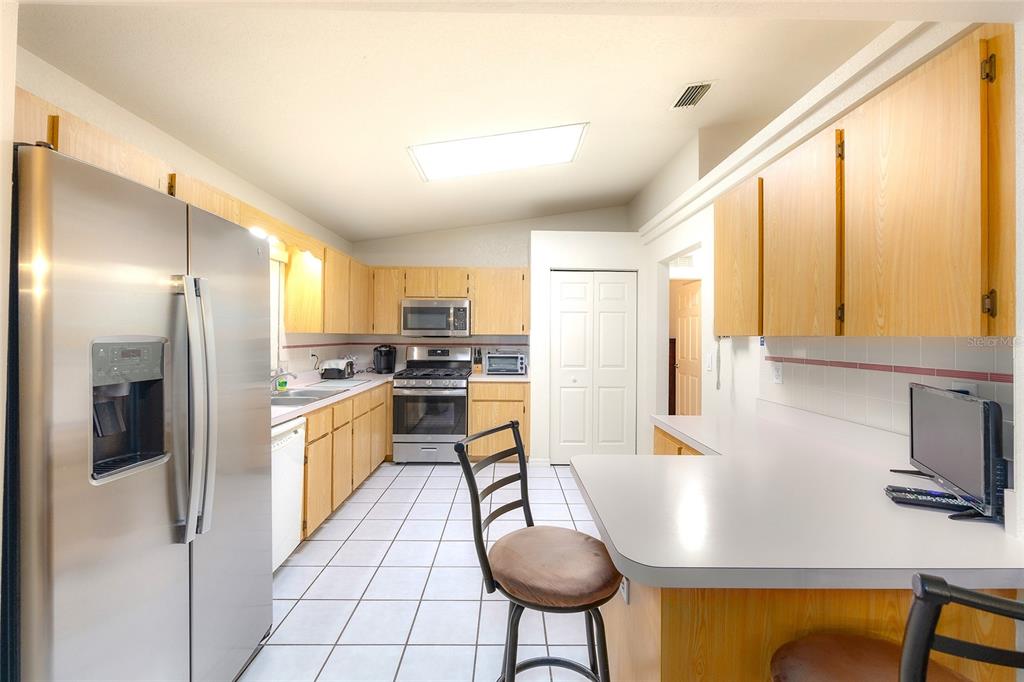 4513 Southwest 158th St Road Ocala, FL 34473 - Photo 15 of 41 a kitchen with stainless steel appliances granite countertop a refrigerator a stove and a wooden cabinets