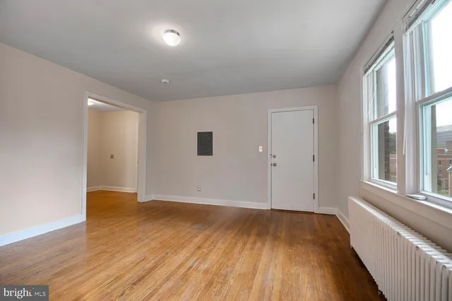 a view of an empty room with wooden floor and a window