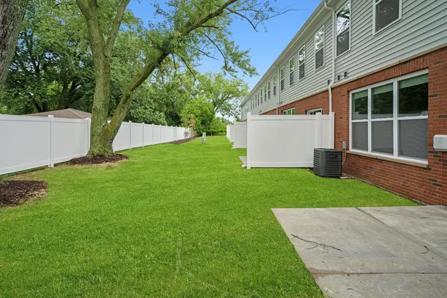 a view of a white house with a yard and a large tree