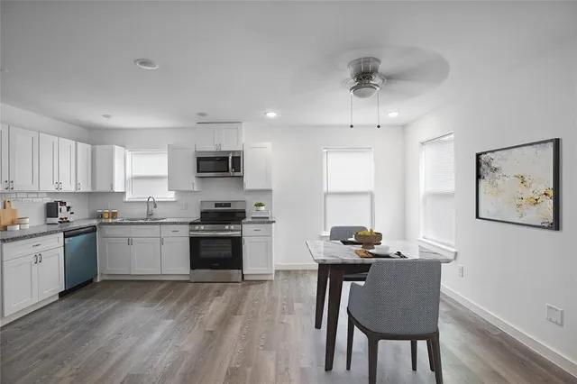 a kitchen with granite countertop a stove top oven a sink dishwasher a dining table and chairs with wooden floor