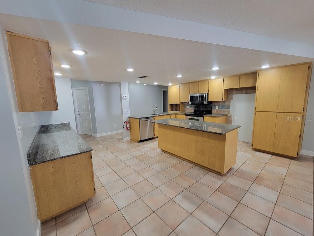 11633 Fox Run Port Richey, FL 34668 - Photo 6 of 33 a kitchen with kitchen island granite countertop a sink and a refrigerator