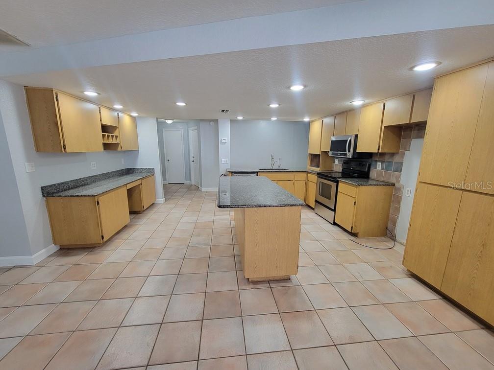 11633 Fox Run Port Richey, FL 34668 - Photo 7 of 33 a large kitchen with granite countertop a large counter top and stainless steel appliances