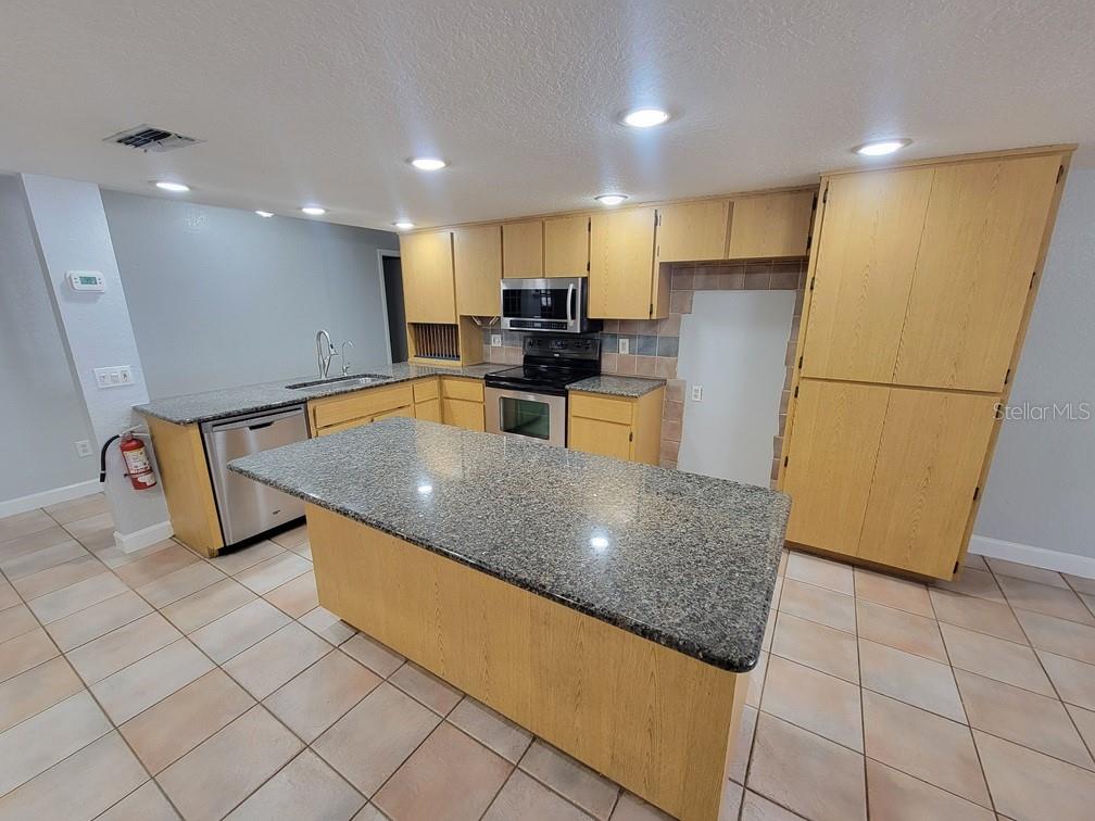 11633 Fox Run Port Richey, FL 34668 - Photo 9 of 33 a kitchen with stainless steel appliances granite countertop a refrigerator a stove a sink a microwave a counter top and cabinets