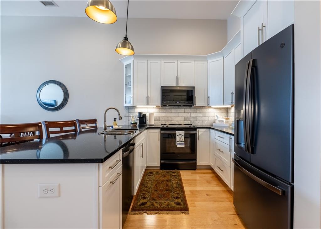 1 East 3rd Avenue, Unit 302 Rome, GA 30161 - Photo 5 of 36 a kitchen with kitchen island granite countertop a sink stainless steel appliances and cabinets