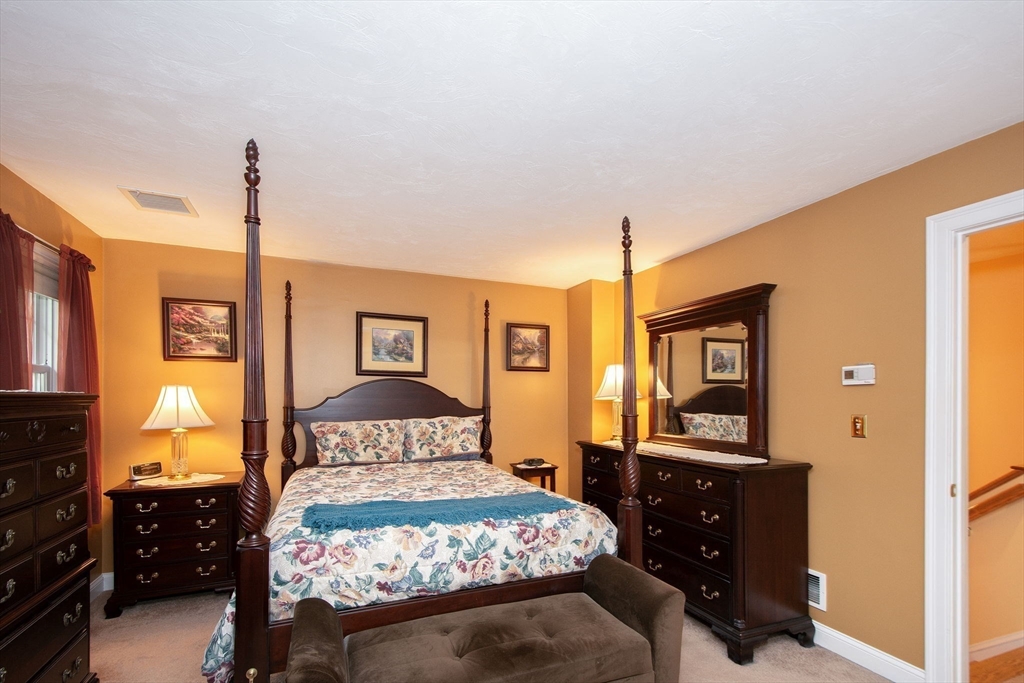 53 Hemlock Circle, Unit 53 Hanover, MA 02339 - Photo 15 of 27 a bedroom with a bed and dresser with mirror