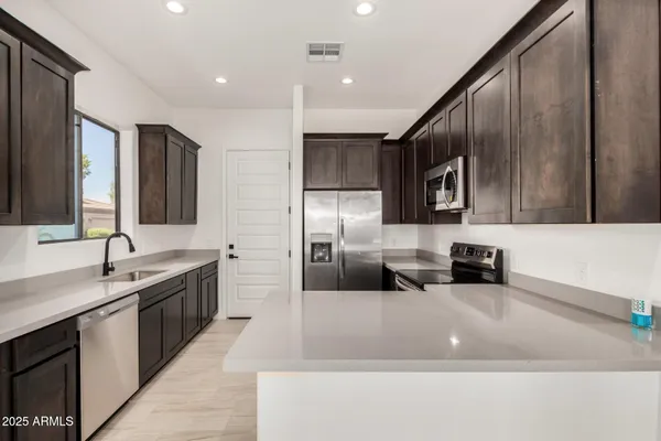 a large kitchen with stainless steel appliances kitchen island granite countertop a sink and a stove top oven with wooden floor
