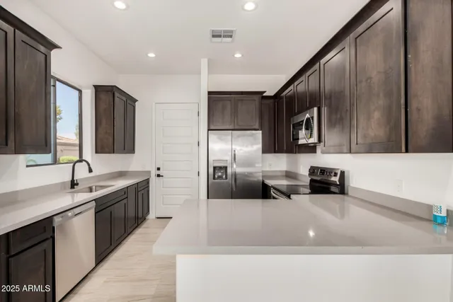 a large kitchen with stainless steel appliances kitchen island granite countertop a sink and a stove top oven with wooden floor