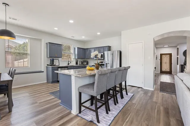 a kitchen with stainless steel appliances kitchen island granite countertop wooden floors and wooden cabinets