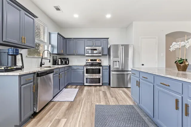 a kitchen with stainless steel appliances granite countertop a refrigerator a stove and a sink with cabinets