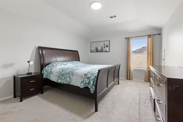 a bedroom with a bed and a lamp on dresser