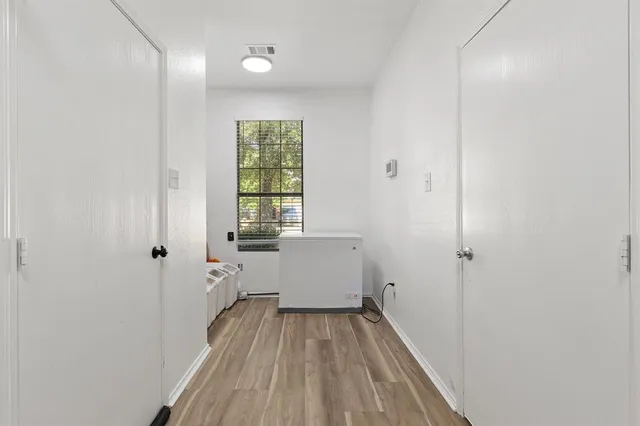 a view of a hallway with wooden floor and a bathroom