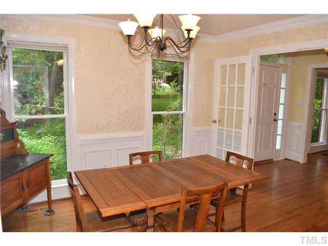 901 Streamer Court Raleigh, NC 27614 - Photo 2 of 21 Formal dining room with hardwood floor, raised paneling, crown molding, two large windows, glass french doors, and an elegant light fixture.