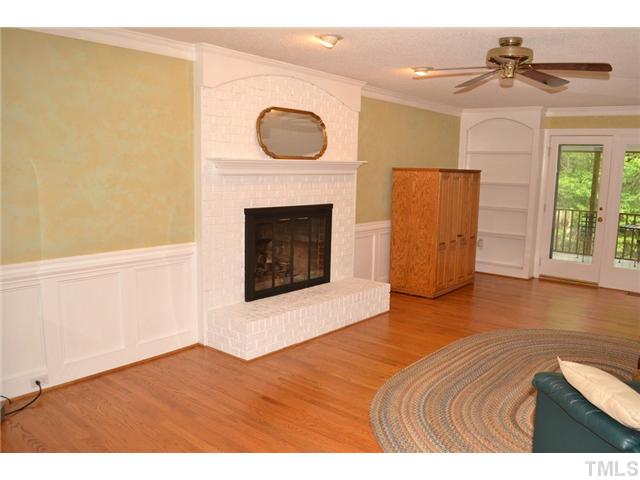 901 Streamer Court Raleigh, NC 27614 - Photo 7 of 21 Another view of the living room featuring a gas log fireplace with brick surround, built-in shelves, and a door to the screened porch