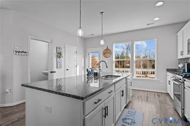 a kitchen with stainless steel appliances granite countertop a sink a stove and a wooden floors