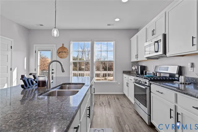 a kitchen with stainless steel appliances granite countertop a sink a stove top oven a counter space and cabinets