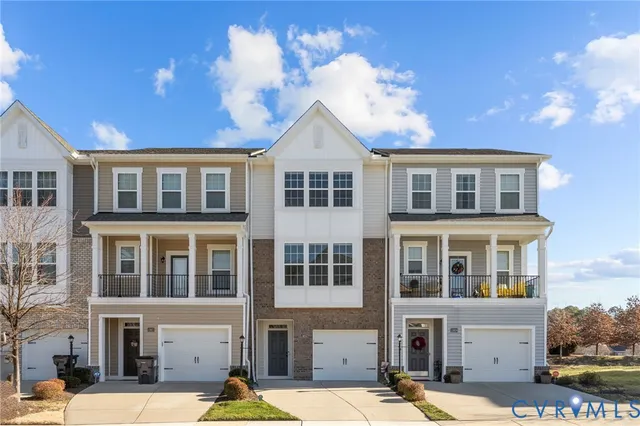 a front view of a building with lot of cars and trees
