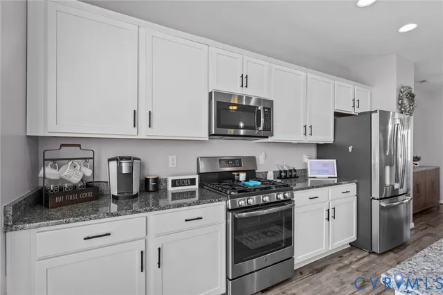 a kitchen with granite countertop white cabinets stainless steel appliances and sink