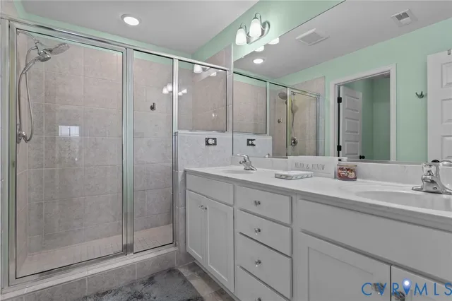 a bathroom with a double vanity sink mirror and shower
