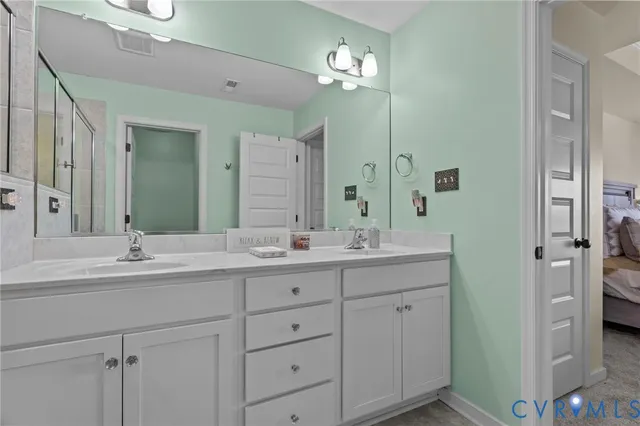 a bathroom with double vanity sinks a vanity a lamp and a mirror
