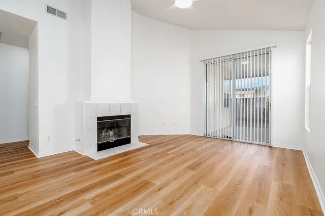 a view of empty room with wooden floor and fireplace