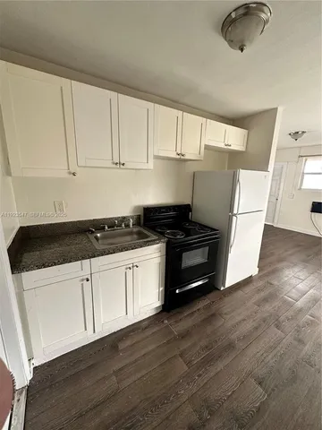 a kitchen with granite countertop white cabinets and black appliances