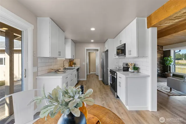 a kitchen with stainless steel appliances granite countertop a refrigerator a stove top oven a sink dishwasher and white cabinets with wooden floor