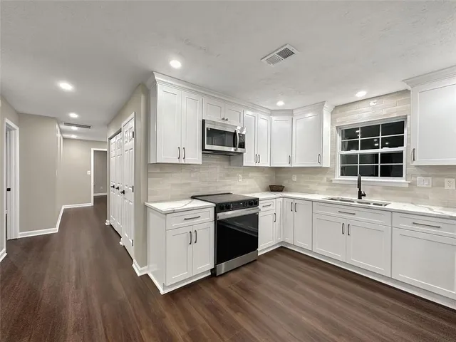 a kitchen with stainless steel appliances granite countertop wooden floors and white cabinets