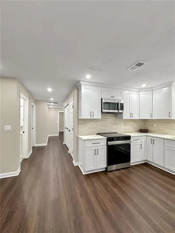 a large kitchen with cabinets wooden floor and stainless steel appliances