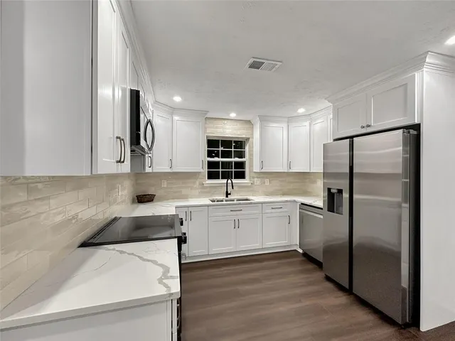 a kitchen with stainless steel appliances granite countertop a refrigerator sink and stove