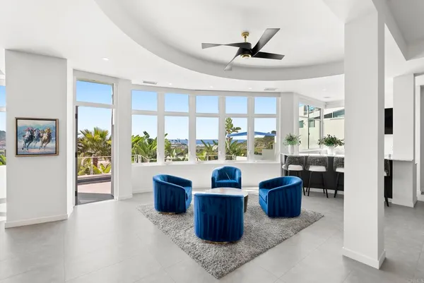 a living room with large couches next to a large window with a dining table and chairs