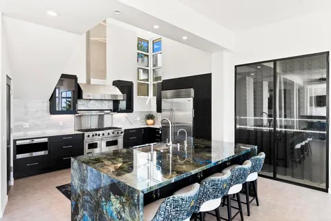 a kitchen with stainless steel appliances kitchen island granite countertop a table chairs and a refrigerator
