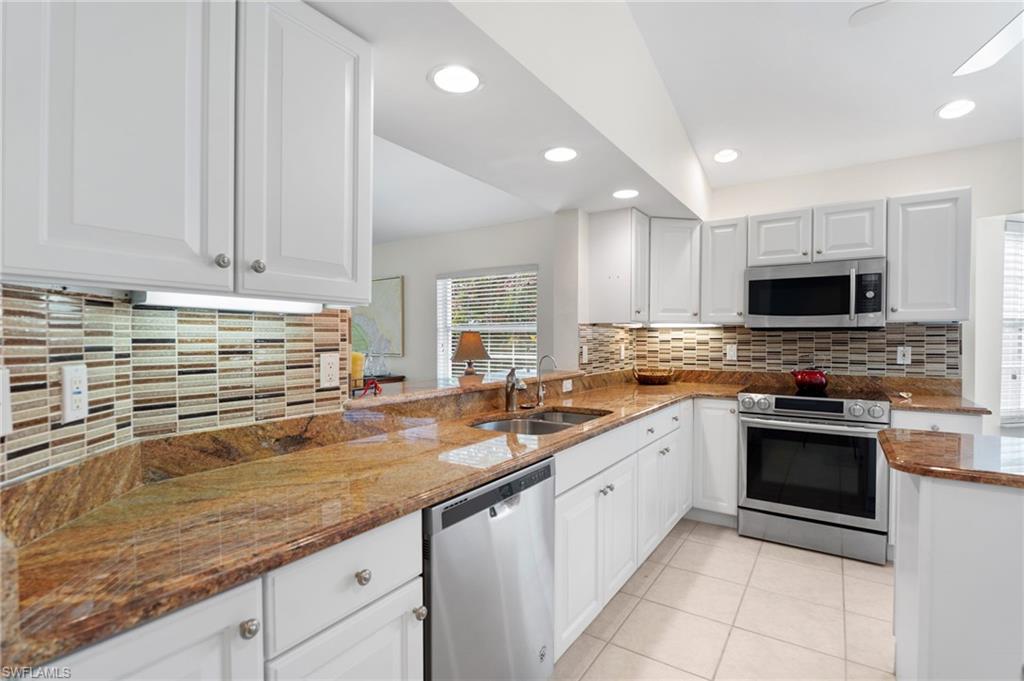 8500 Mystic Greens Way, Unit 506 Naples, FL 34113 - Photo 21 of 48 a kitchen with granite countertop a sink stainless steel appliances and white cabinets
