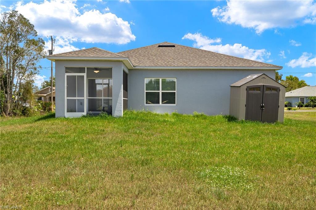 858 Rue Labeau Circle Fort Myers, FL 33913 - Photo 14 of 19 Back of property with a sunroom, a storage shed, and a yard