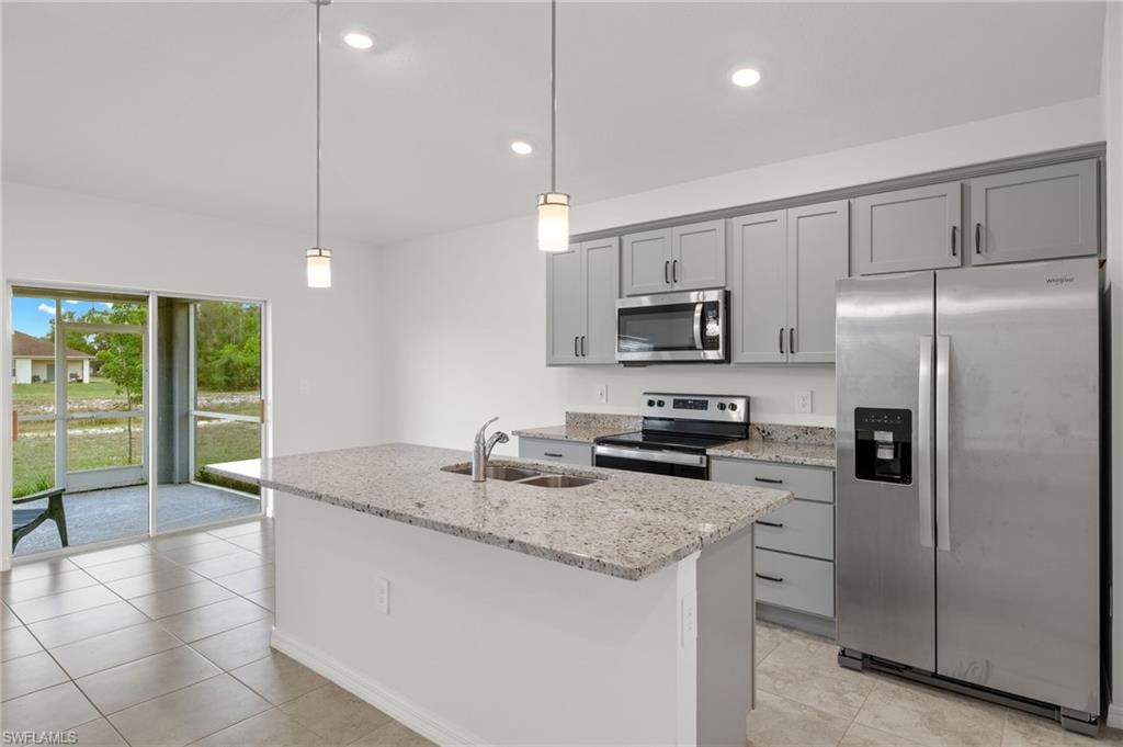 858 Rue Labeau Circle Fort Myers, FL 33913 - Photo 4 of 19 Kitchen featuring light tile flooring, stainless steel appliances, hanging light fixtures, a kitchen island with sink, and sink