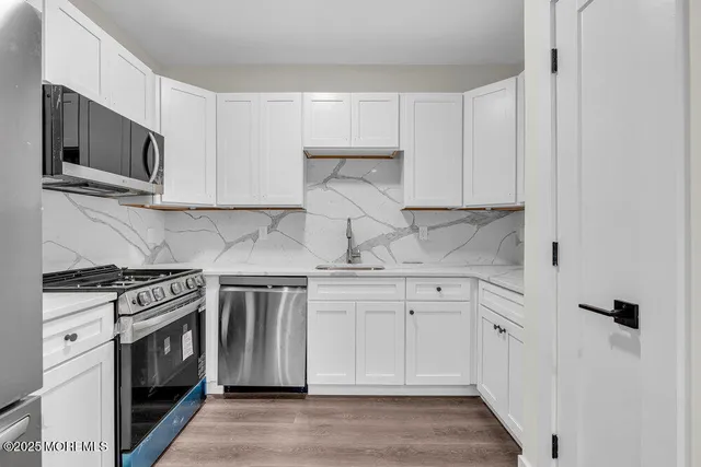 a kitchen with stainless steel appliances white cabinets and a stove top oven