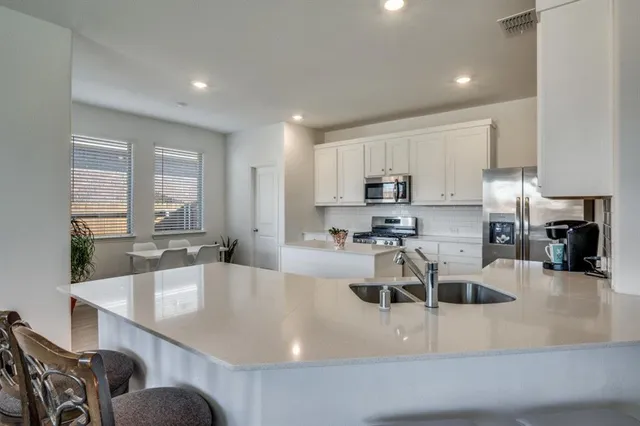 a large white kitchen with cabinets a sink a window and stainless steel appliances