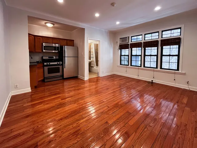a view of an empty room with a kitchen and a window