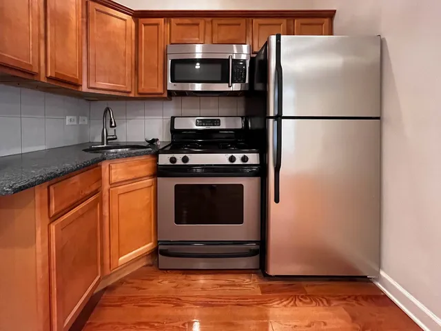 a kitchen with stainless steel appliances granite countertop a refrigerator a stove a sink and dishwasher