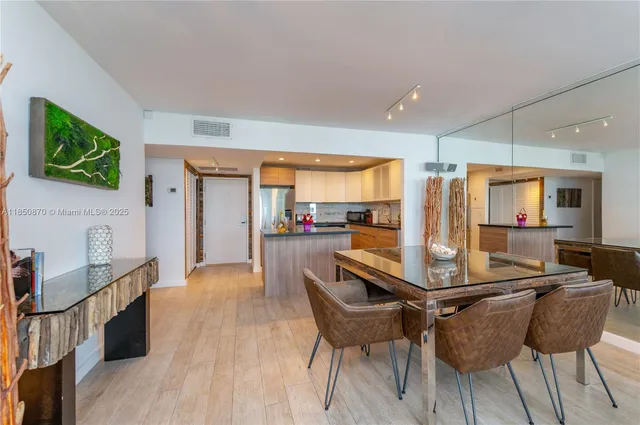 a kitchen with stainless steel appliances kitchen island granite countertop a stove a refrigerator a sink a dining table and chairs with wooden floor