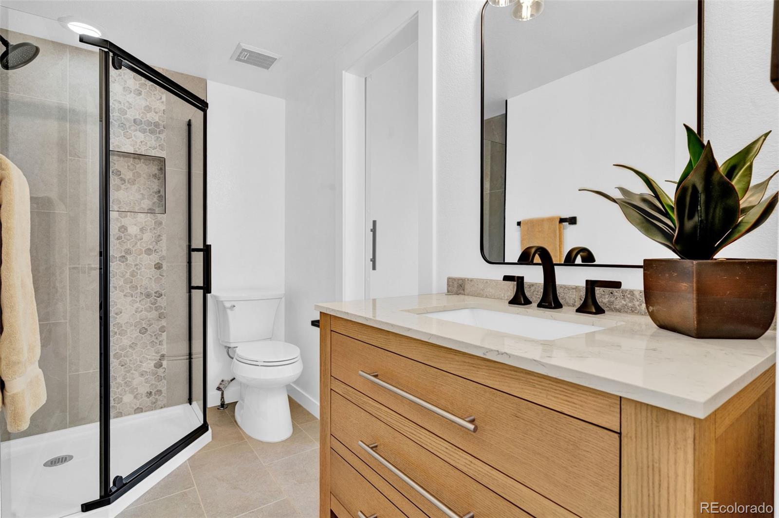 5051 Garrison Street, Unit 7C Wheat Ridge, CO 80033 - Photo 16 of 27 a bathroom with a granite countertop sink a toilet and a mirror
