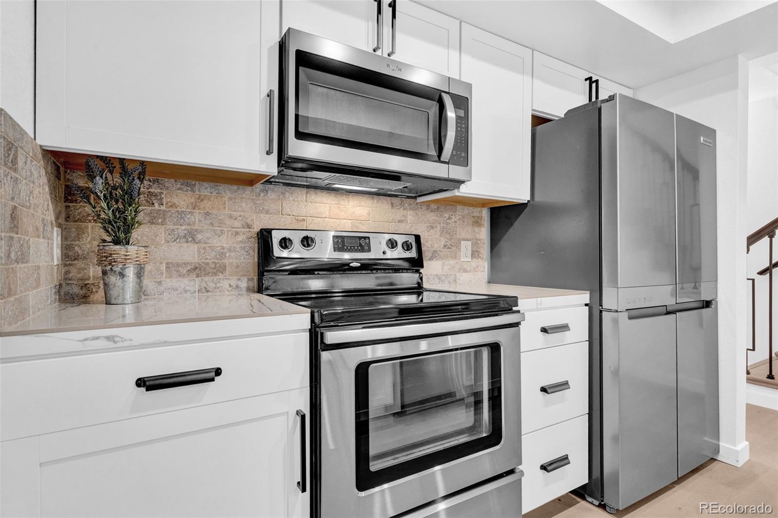 5051 Garrison Street, Unit 7C Wheat Ridge, CO 80033 - Photo 2 of 27 a kitchen with stainless steel appliances white cabinets white stove a microwave and a refrigerator