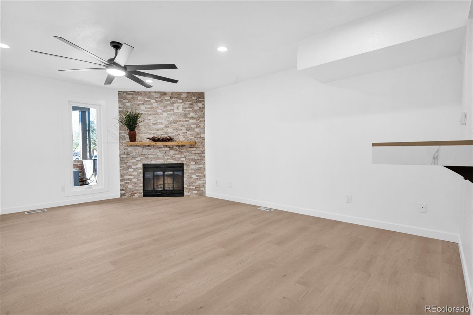 5051 Garrison Street, Unit 7C Wheat Ridge, CO 80033 - Photo 7 of 27 an empty room with fireplace and windows