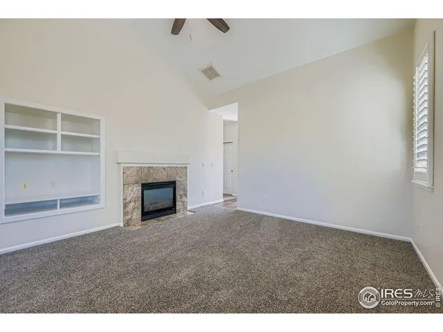 a view of an empty room with a fireplace and a window